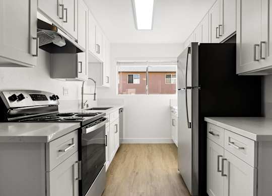 A kitchen with white cabinets and a black refrigerator.