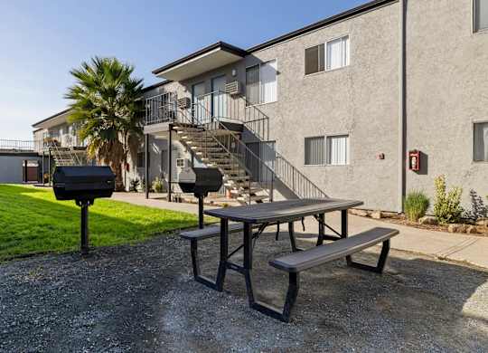 A picnic table is in front of a building with a palm tree.