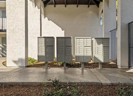 A row of mailboxes are lined up on a sidewalk.