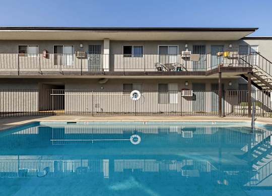 A pool in front of a building with a staircase on the right side.