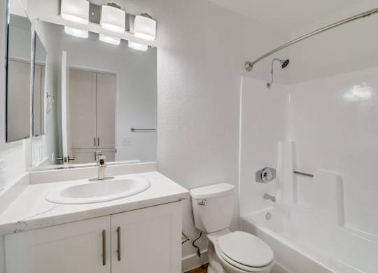 A white bathroom with a sink, toilet, and bathtub.
