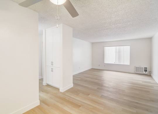 A room with a ceiling fan and a window with blinds.