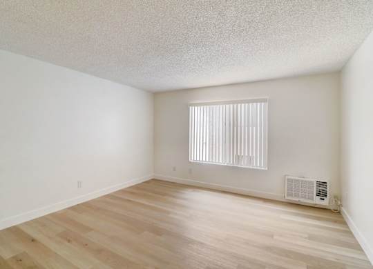 A room with wooden floors and a window with blinds.