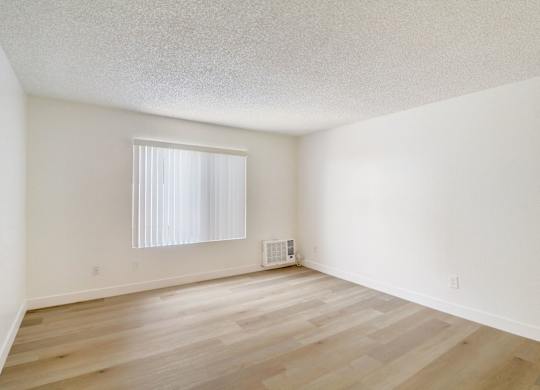 A room with wooden flooring and a window with blinds.