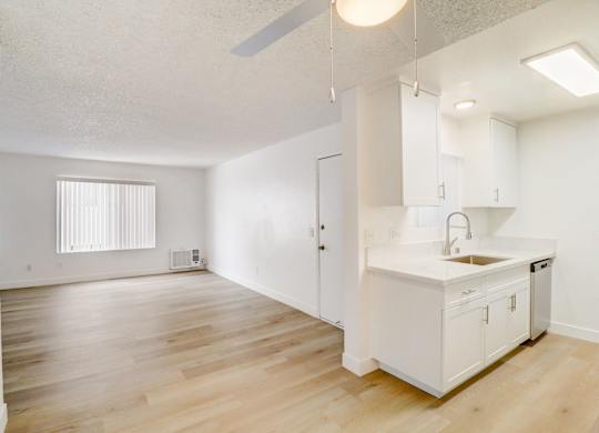 A kitchen with white cabinets and a wooden floor.