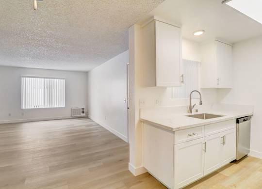 A kitchen with white cabinets and a wooden floor.