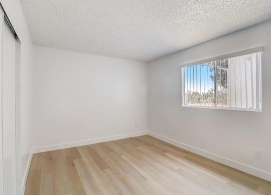 A room with a window and wooden flooring.