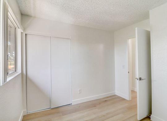 A room with a white door and a window on the left.