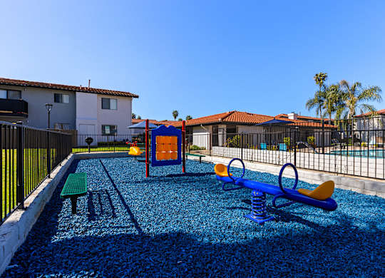 A playground with a blue slide and a yellow swing set.