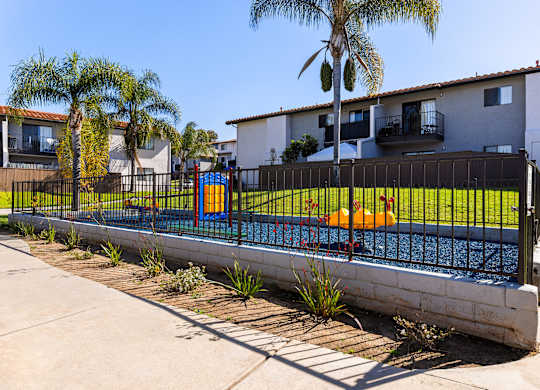 A pool surrounded by a black fence with a small orange boat in the water.