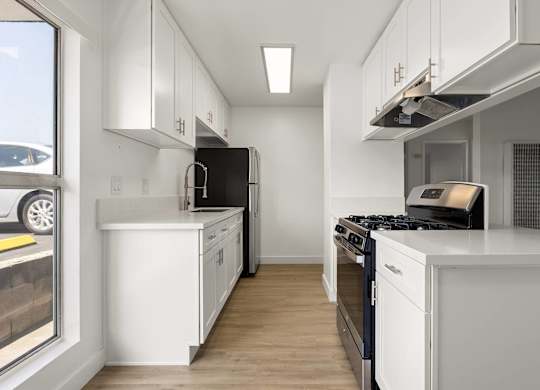 A modern kitchen with white cabinets and black appliances.