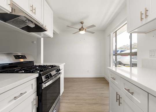 A white kitchen with a black stove top oven.
