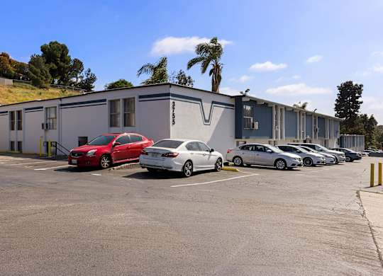 A parking lot with cars and a building in the background.