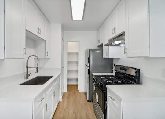 A kitchen with white cabinets and black appliances.