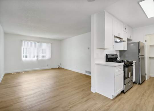 A kitchen with white appliances and wooden floors.