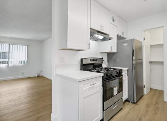 A white kitchen with a stove, oven, and refrigerator.