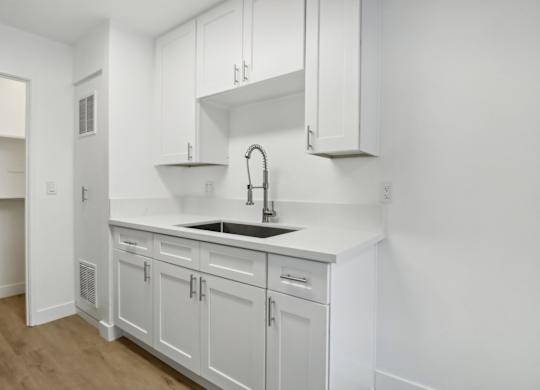 A white kitchen with a sink and cabinets.