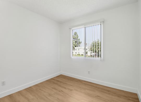 A room with a window and wooden flooring.