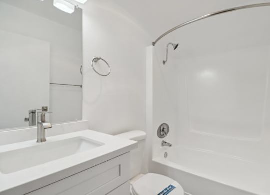 A white bathroom with a toilet, sink, and bathtub.