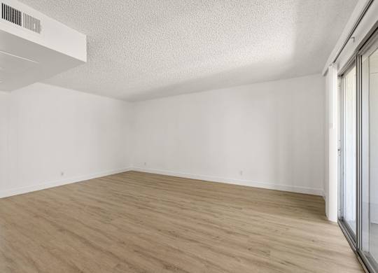 A room with wooden flooring and white walls.