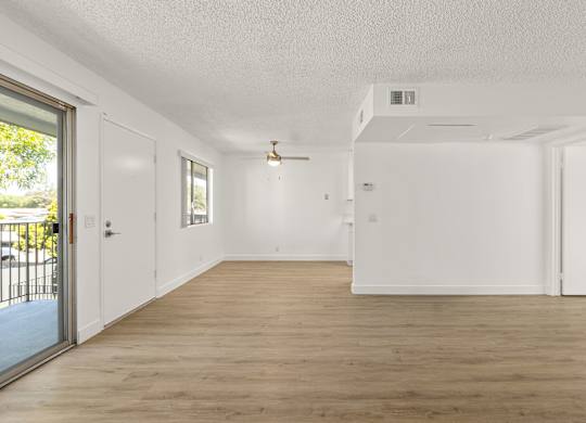 A spacious room with wooden flooring and white walls.