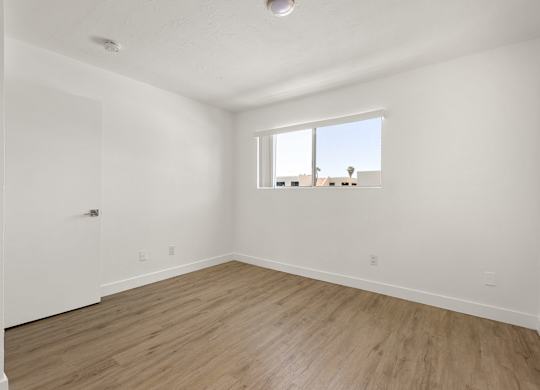 Empty room with a window and wooden flooring.