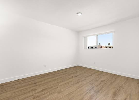 Empty room with wooden floor and a window.
