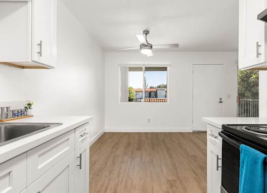A kitchen with white cabinets and a wooden floor.