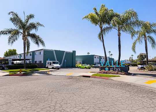 A parking lot with a building and palm trees in the background.