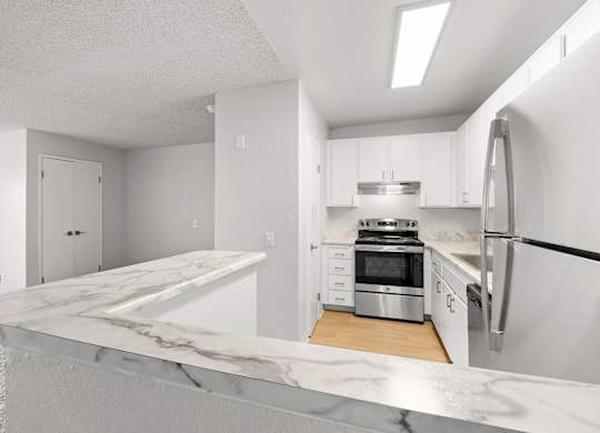 A modern kitchen with a marble countertop and stainless steel appliances.