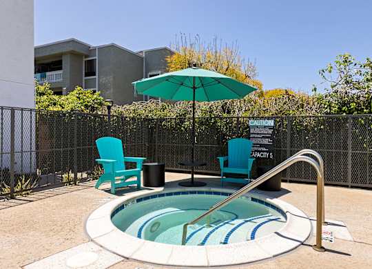 A small pool with a blue striped border and a metal fence surrounding it.
