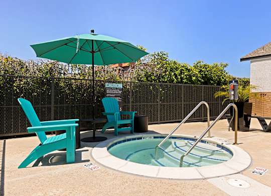 A small pool with a hot tub and two chairs.