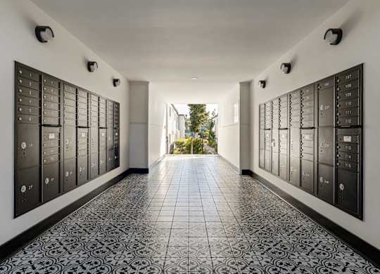 A long hallway with black and white tiles and a black wall with many mailboxes.