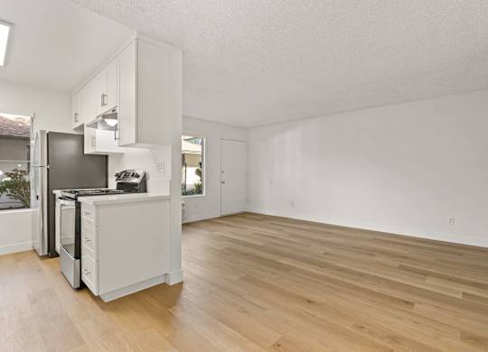 A kitchen with white cabinets and a wooden floor.