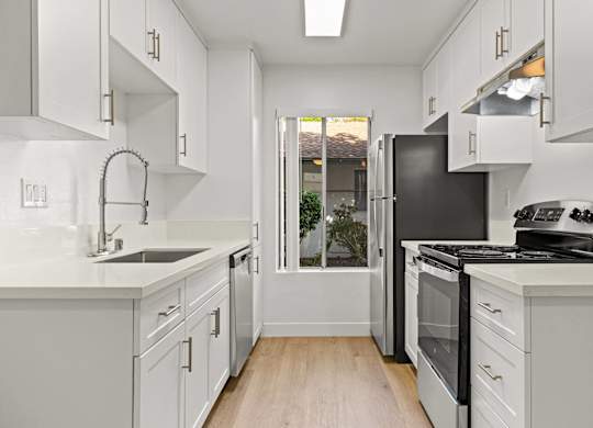 A kitchen with white cabinets and a black refrigerator.