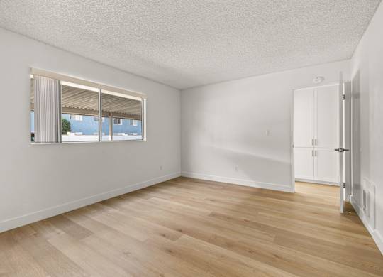 A room with a window and wooden flooring.