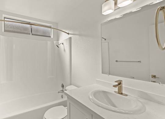 A white bathroom with a toilet, sink, and tub.
