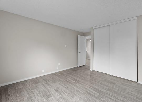 A room with a white door and a wooden floor.