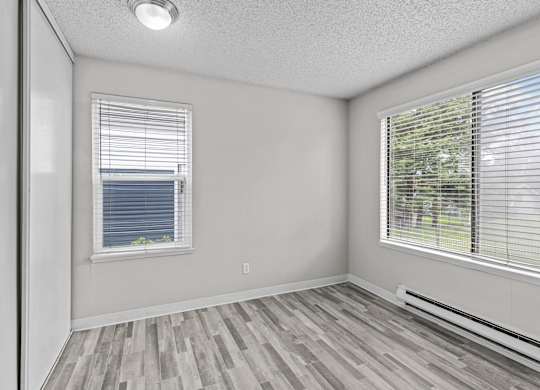 A room with a window and a wooden floor.