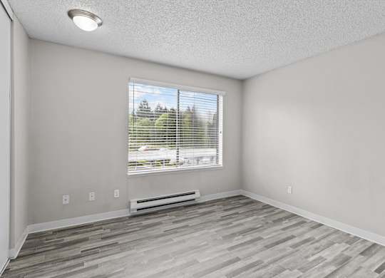 A room with a window and a wooden floor.