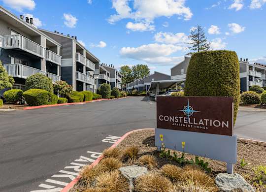 A sign for Constellation Apartments is in the foreground of a road.