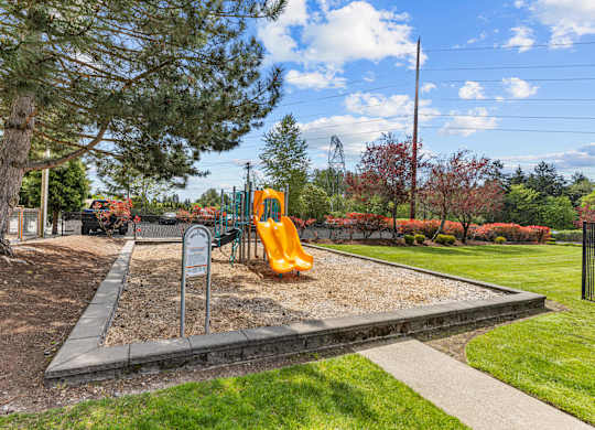 A playground with a yellow slide and a sign.