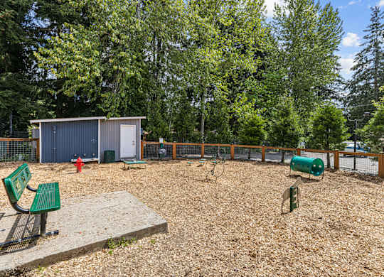 A playground with a green bench and a brown sandbox.