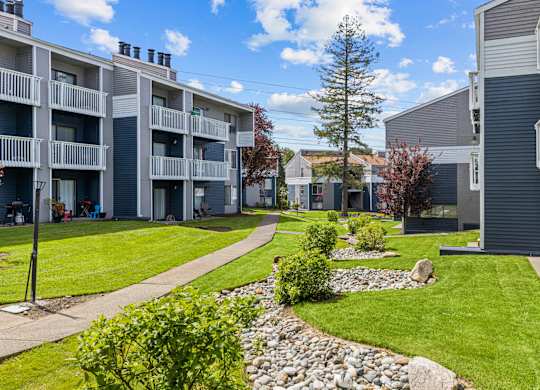 Apartment complex with a grassy area and a stone path.