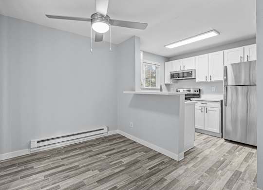 A kitchen with a refrigerator, stove, and cabinets.