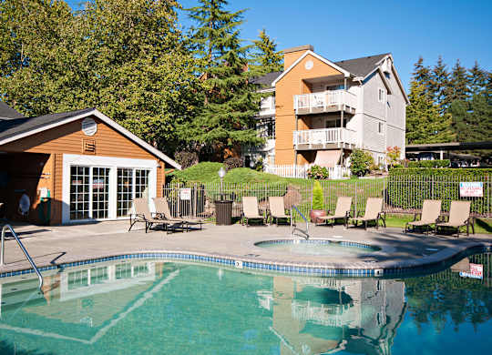 A swimming pool with a slide and chairs around it.