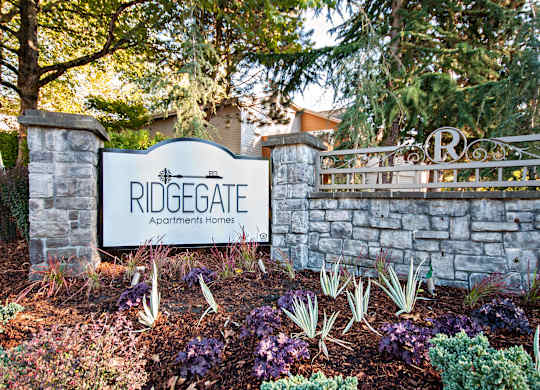 A sign that says Ridgegate Apartments Homes stands in front of a wall.