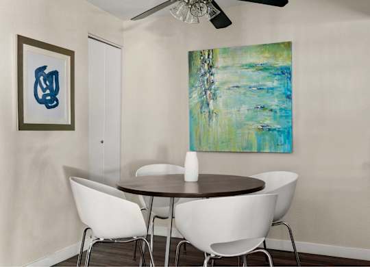 A painting hangs on the wall above a table with chairs.