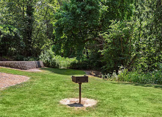 A signpost stands in a grassy area with a forest in the background.