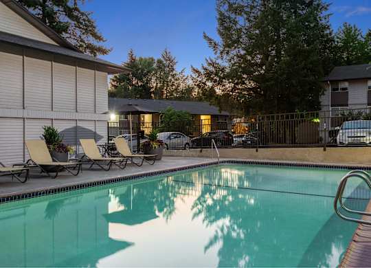 A pool with a metal ladder and a few chairs.